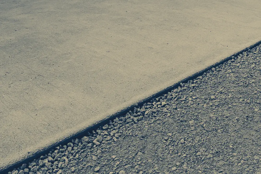 A plain strip of bare level concrete with a narrow band of gravel along one edge — block wall, Idaho Falls. Illustrative example.